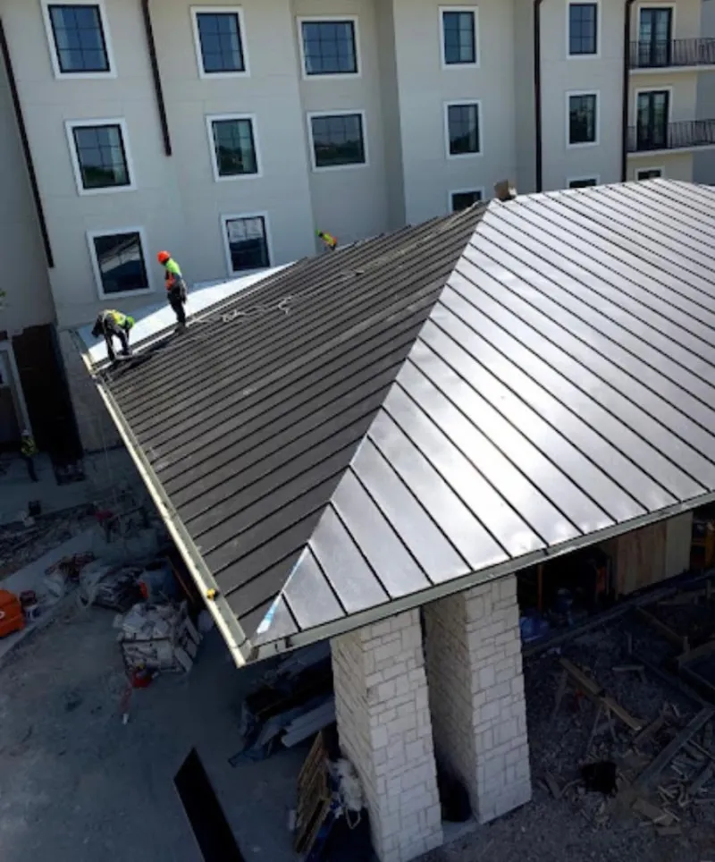 Crew installing standing seam metal roof panels on a commercial project in Volo